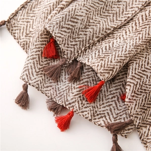 Close-up of herringbone knit fabric with brown and beige patterns and dual-tone tassels