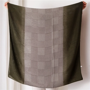 Detail of a green and khaki houndstooth scarf showing the fine woven texture and color blocks