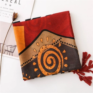 Detailed view of bohemian cotton linen scarf with abstract spiral patterns and red tassels