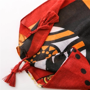 Detailed close-up of ethnic totem print and red tassel fringe on lightweight cotton linen scarf