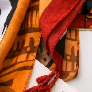 Close-up of ethnic style printed scarf with warm tones and fine red fringe tassels