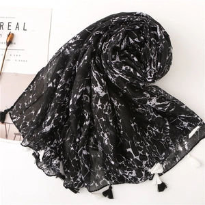 Detail of cotton linen scarf featuring black marble pattern and elegant tassel edges