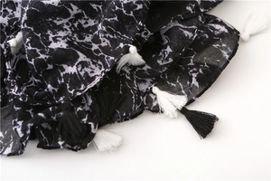 Detail of cotton linen scarf showing marble print pattern and black and white tassel fringe