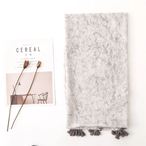 Detail of light gray marble patterned scarf with elegant gray tassels on white background