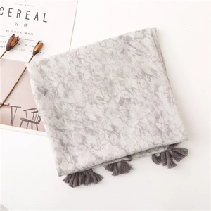 Detail of marble pattern scarf with grey tassels on a white background with dried flowers