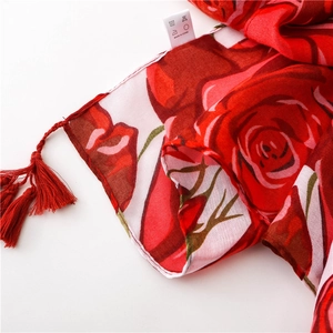 Close-up of red rose print scarf with delicate fringe tassels and cotton linen texture