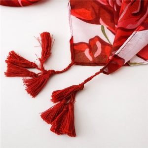 Detailed view of red floral cotton linen scarf with intricate woven fringe tassels