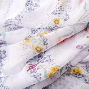 Dettaglio del tessuto leggero in cotone bianco con eleganti stampe floreali colorate