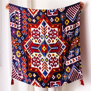 Détail du châle de plage bleu marine avec motifs géométriques et pompons rouges