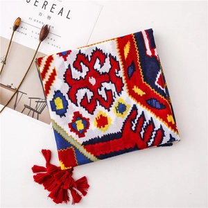 Détail d'écharpe à motifs géométriques avec pompons rouges et imprimé bohème sur fond blanc