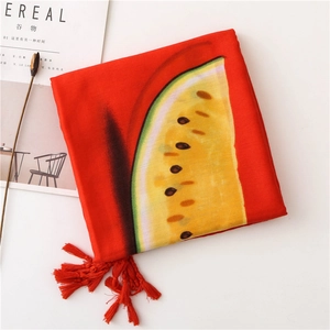 Détail d'une écharpe rouge à motif pastèque avec pompons et texture coton élégante