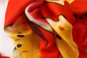 Vue détaillée du foulard imprimé pastèque avec pompons rouges et texture respirante