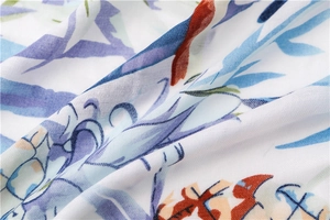 Gros plan sur l'imprimé perroquet tropical et floral d'une écharpe en coton-lin