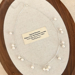 Elegant silver pearl necklace with white round pearls displayed on a wooden tray