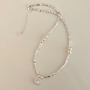 Collana stile francese con perle e pendente in zircone su sfondo grigio chiaro
