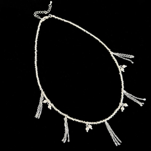 Detailed view of silver beaded necklace with white pearls and hanging fringe tassels