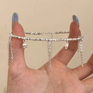 Detailed view of silver tassel bracelet with faceted beads and dangling pearls