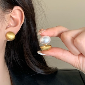 Macro detail of French vintage pearl earrings with matte gold base on ear and in hand
