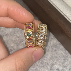 Close-up of golden adjustable rings with colorful and clear rectangular cubic zirconia