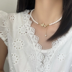 Elegante Perlenhalskette mit Schmetterlingsanhänger und Golddetails am Hals der Frau
