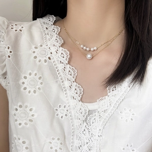Elegant double-layered gold chain necklace featuring polished pearls for a French chic look