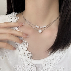 Elegant double-layer pearl necklace with silver-tone chain on a female model neck
