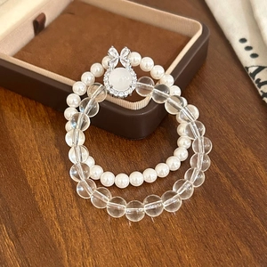 Detail of double-layer bracelet with white pearls and clear crystal beads on wooden surface