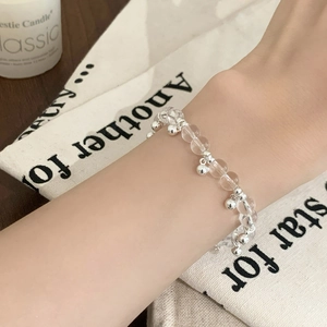 Minimalist beaded bracelet featuring clear crystal beads and silver charms on wrist