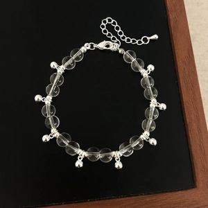Retro transparent glass bead bracelet with silver bells on black jewelry display stand