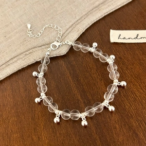 Detail view of a handmade transparent glass bead bracelet with silver metal charms and clasp