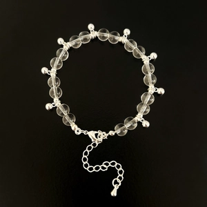 Detail of transparent glass bead bracelet with silver charms and lobster clasp closure