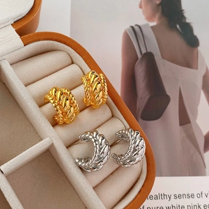Close-up of twisted gold and silver hoop earrings inside a luxury jewelry gift box