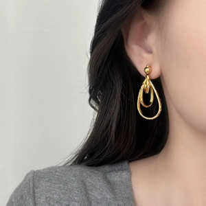 Boucles d'oreilles dorées en forme de goutte d'eau avec texture martelée sur mannequin