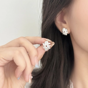 Elegant silver woven earrings with pavé zircons shown on ear for a modern bridal look