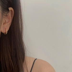 Minimalist gold hoop earrings with micro-paved cubic zirconia worn on a model's ear