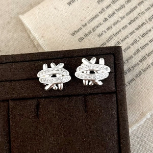 Macro detail of silver woven stud earrings with pavé cubic zirconia on jewelry tray