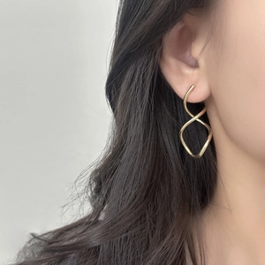 Fashionable geometric twisted gold earrings with a minimalist spiral design on a model