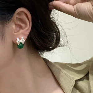 Close-up of green spherical stud earrings with bow tie cubic zirconia crystal accents