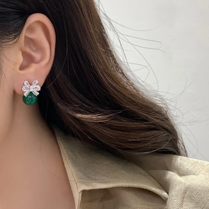 Elegant crystal bow earrings with green pendant pearls shown on a female model