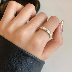 French style gold ring with white enamel and embossed floral patterns on model's hand