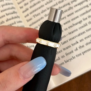 Detailed close-up of a gold enamel ring with white flowers on a black display stand