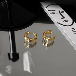 Detailed view of gold bamboo style hoop earrings on a high-gloss black reflective surface