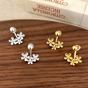 Floral cluster stud earrings in gold and silver finish on a rustic wooden tray