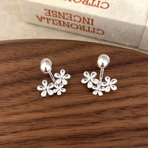 Detailed view of silver flower stud earrings on dark wood tray with white gift box