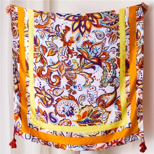 Detail of bohemian paisley print shawl featuring light fabric and red tassel accents