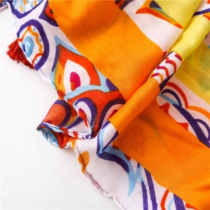 Detail of bohemian shawl with colorful geometric patterns and decorative red fringe