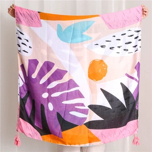 Detail of bohemian floral print scarf with pink tassels and abstract monstera leaf patterns