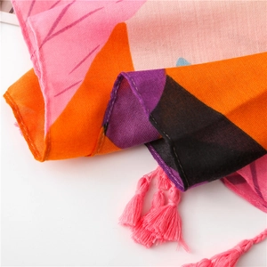 Close-up of bohemian linen scarf featuring vibrant floral prints and pink tassel trim
