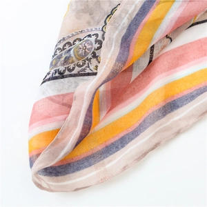 Detail of bohemian cotton scarf featuring orange paisley patterns and sheer texture