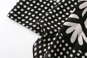 Close-up of black fabric featuring white polka dots and floral pattern with fine texture